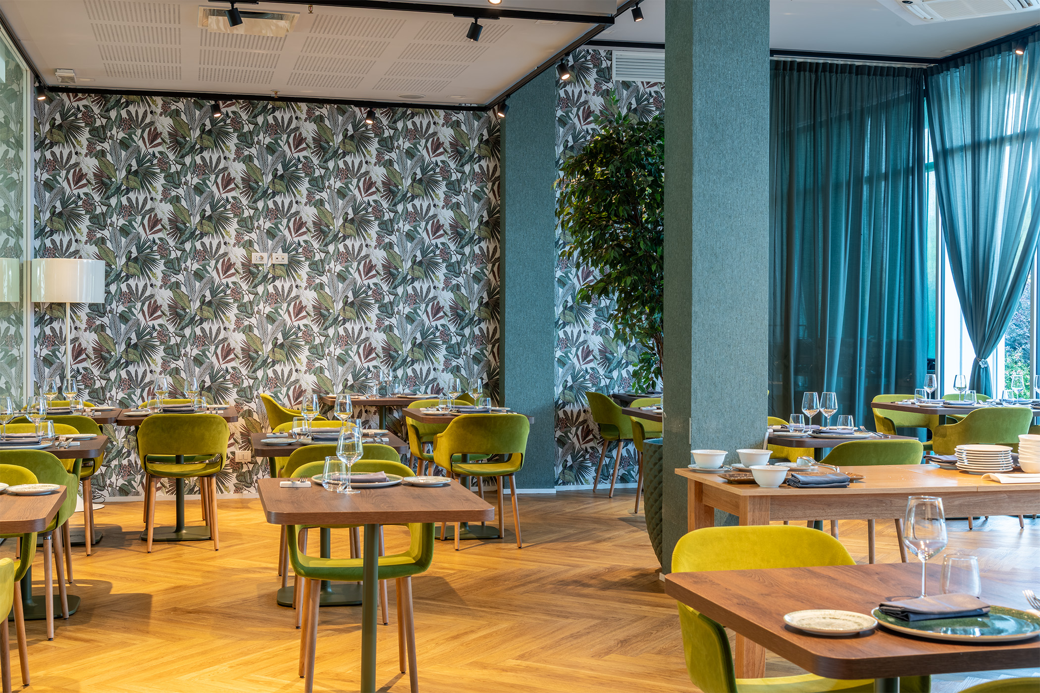 Dining room of Bloom Restaurant & Lounge Bar at Moom Hotel, featuring set tables, designer chairs, and a bright garden view