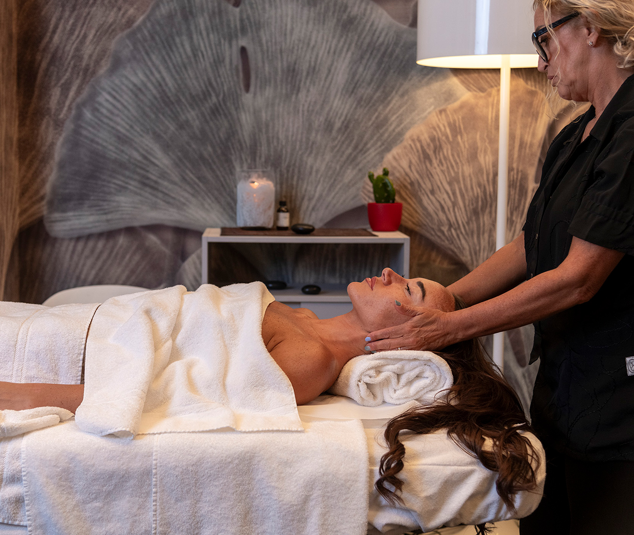 A guest enjoying a facial and head massage while lying on a massage table