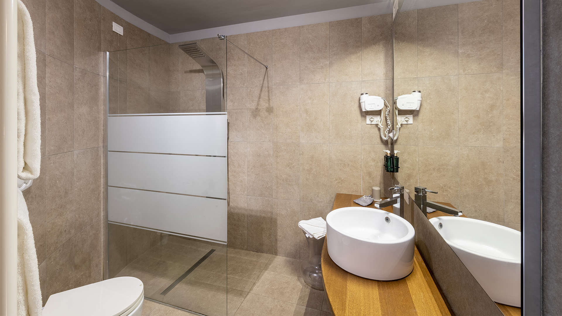 Luxurious Deluxe room bathroom: light beige walls, natural light, white sink, and transparent open shower