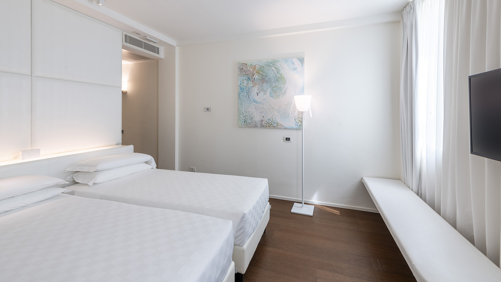 Elegant Superior room: white walls, large windows, abstract painting, wooden floor, and two beds for relaxation